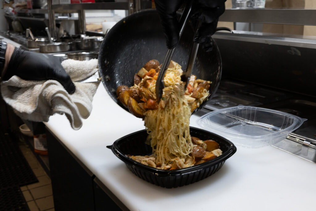 Fire & Feast chef preparing a fresh sautéed entrée for a catering event in Commerce Township, Michigan.