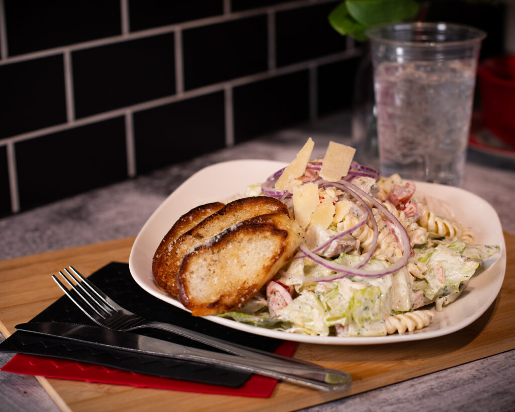 The Salad from Fire & Feast featuring fresh lettuce, roasted turkey breast, rotini pasta, tomatoes, cucumbers, croutons, and ranch dressing in Commerce Township, Michigan.