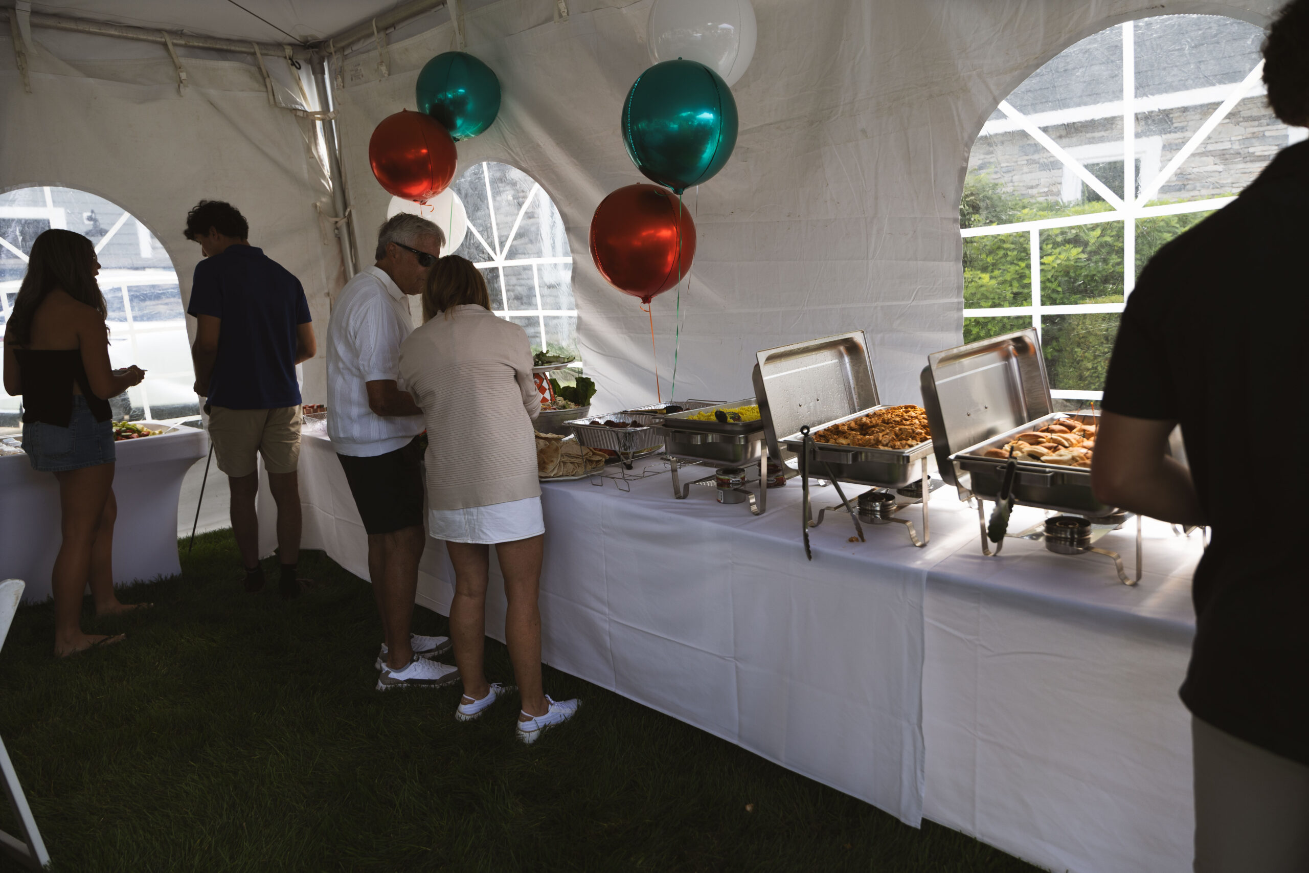 Guests serving themselves from a Fire & Feast catering buffet at a birthday party in Commerce Township, Michigan.