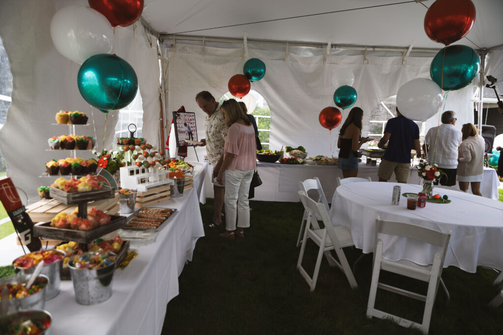 Guests serving themselves from a Fire & Feast catering buffet featuring fresh Mediterranean specialties and American favorites at a private event in Commerce Township, Michigan.