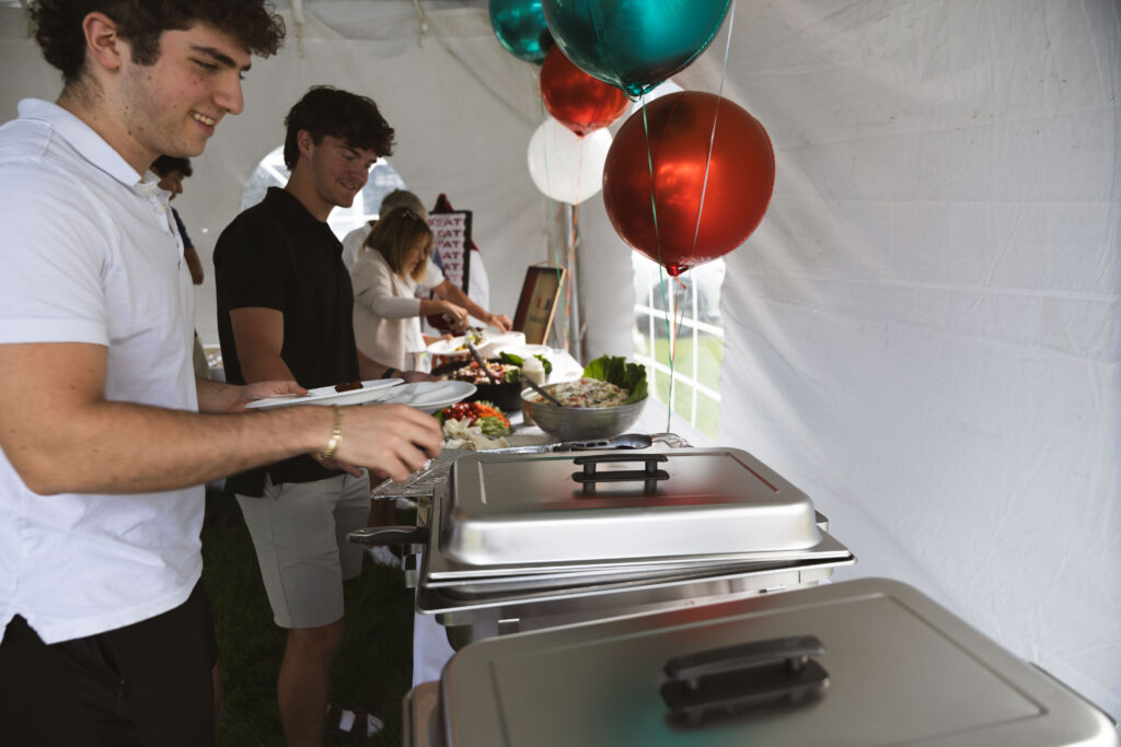 Guests enjoying Fire & Feast catered food at an outdoor celebration in Commerce Township, Michigan.
