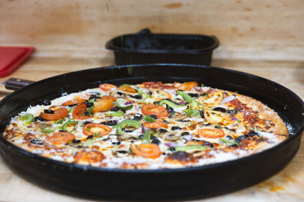Freshly baked Fire & Feast artisan pizza with premium cheese and fresh toppings in Commerce Township, Michigan.