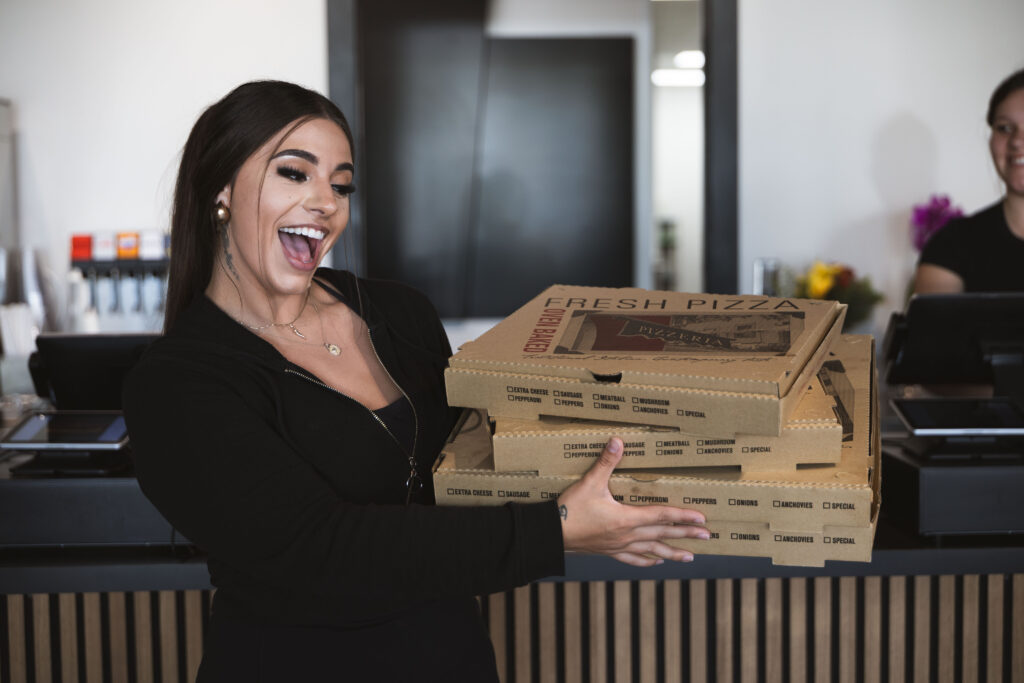Customer picking up freshly made Fire & Feast gourmet pizzas at our carry-out restaurant in Commerce Township, Michigan.